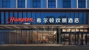 Een hotelentree met een modern ontwerp, met grote glasramen en een opvallend bord.