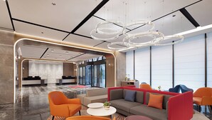 Een moderne lobby met een receptiebalie, een zithoek en grote ramen.