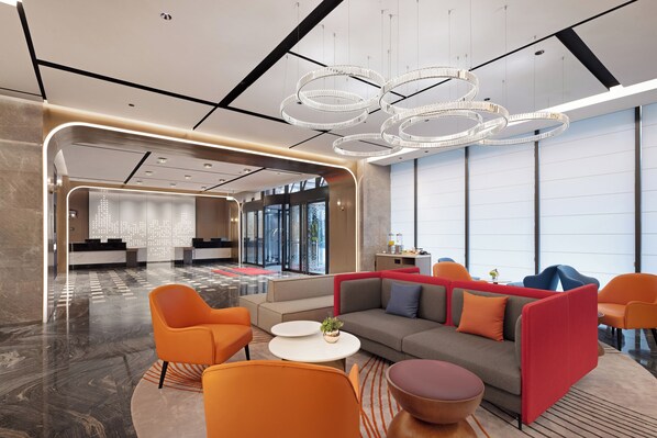 A modern lobby with a reception desk, seating area, and large windows.