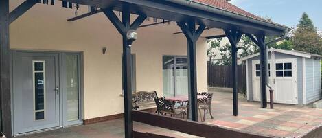A covered patio area with a table and chairs, a small shed, and a door leading to a garage.
