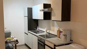 Una cocina compacta con horno integrado, cafetera y refrigerador.