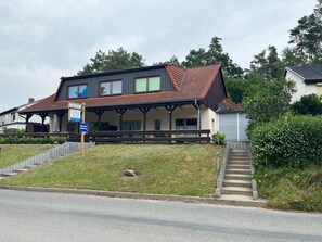 Een gebouw met twee verdiepingen, een overdekte veranda, een bordje dat een restaurant aangeeft, en een trap naar de ingang.