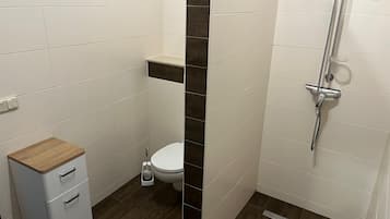 Ein Badezimmer mit Toilette, Dusche und Stauraum.