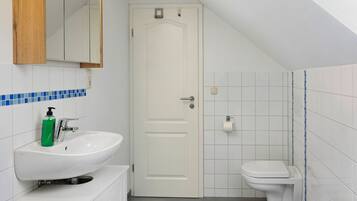 A bathroom with a white sink, a mirror, a toilet, and a door.