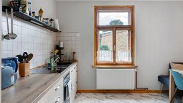Une cuisine avec une fenêtre, des carreaux blancs, un plan de travail en bois et un radiateur.
