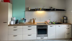 A kitchen with white cabinets, a stainless steel oven, a coffee maker, and a red container on the counter.