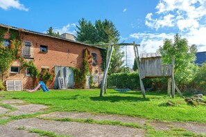 A brick building with a swing set and a slide in the yard. - Holiday Apartment 'Pieck' with Shared Garden and Wi-Fi (Raduhn)