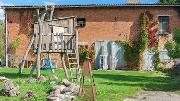 Un edificio rústico de ladrillo con un parque infantil de madera y una escalera.