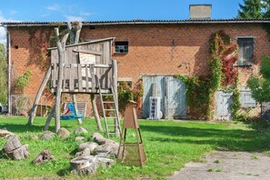 Un edificio rústico de ladrillo con un parque infantil de madera y una escalera.