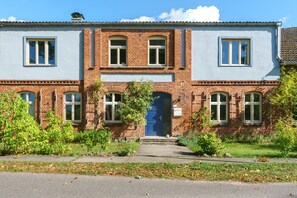 A two-story building with a blue door, multiple windows, and a brick facade. - Holiday Apartment 'Pieck' with Shared Garden and Wi-Fi (Raduhn)