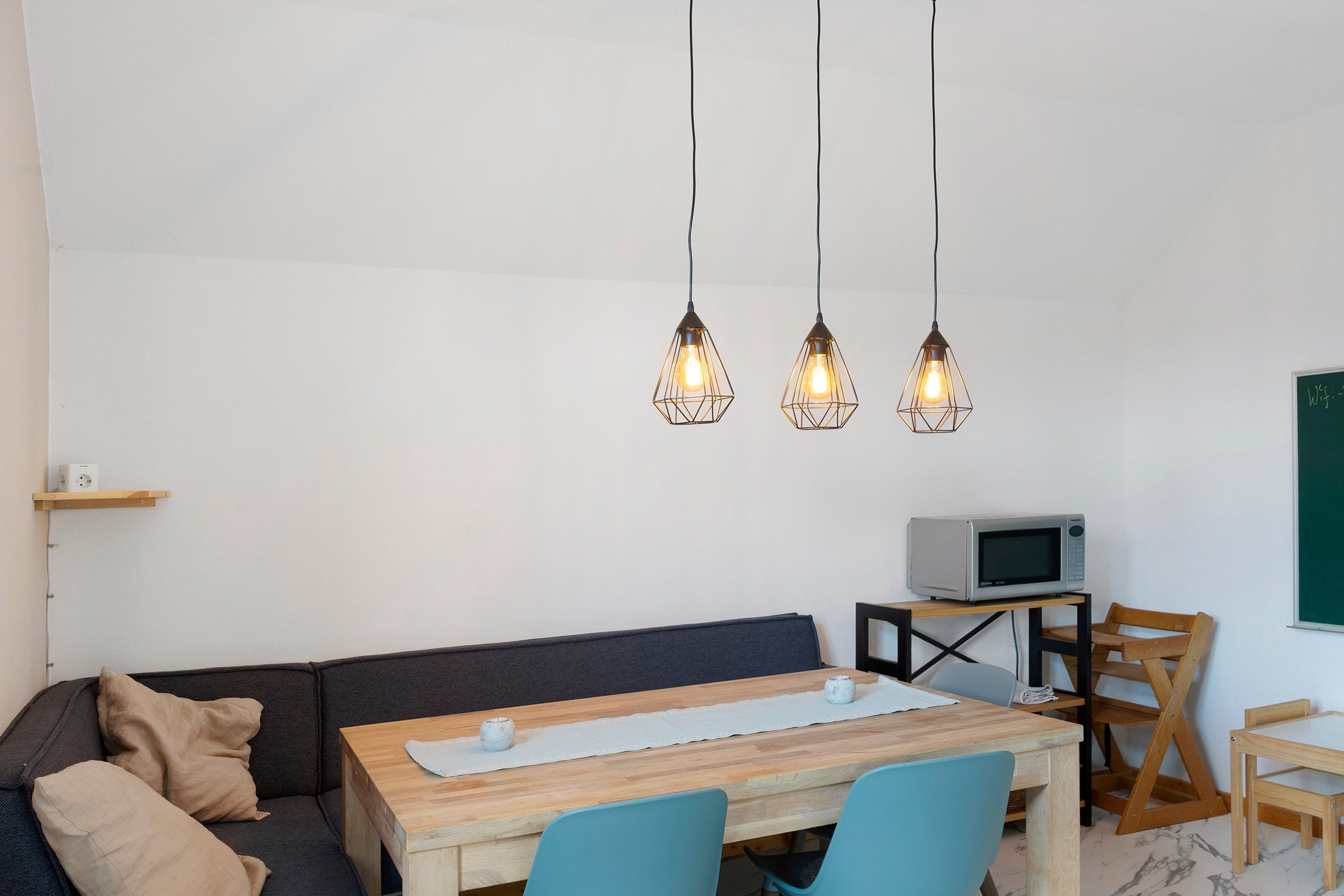 Un espacio moderno para vivir con sofá, mesa de comedor de madera y televisor sobre un mueble bajo.