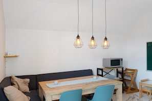 En moderne stue med sofa, et træspisebord og et fjernsyn på et stativ.