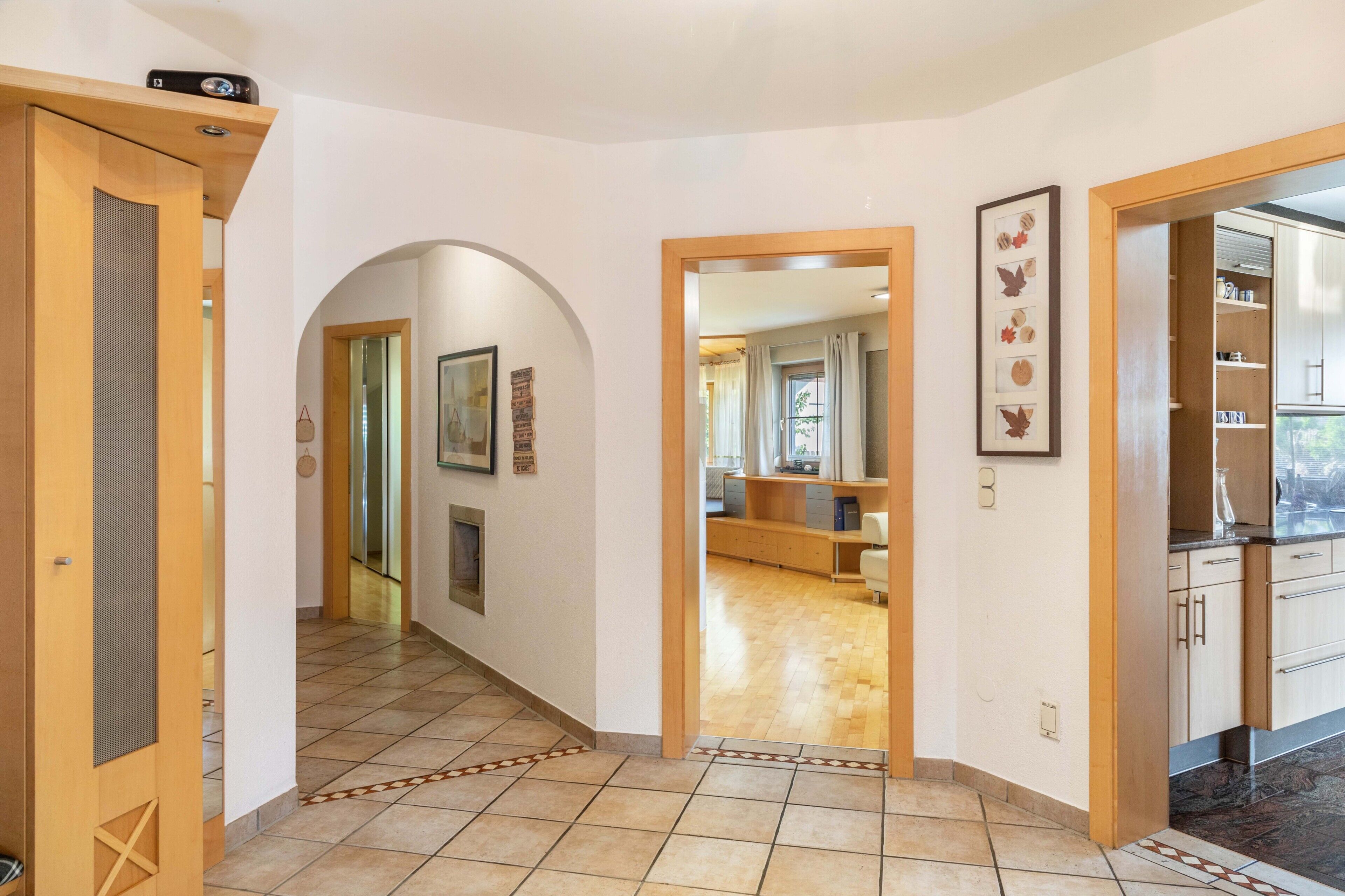 A hallway with a wooden door, a framed picture, and a tiled floor.