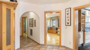 A hallway with a wooden door, a framed picture, and a tiled floor.