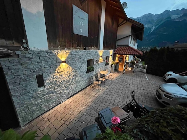 A stone wall with a sign, outdoor seating, and a mountain view.