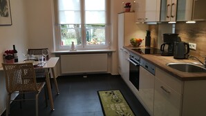 Une cuisine compacte avec un coin repas, une fenêtre offrant une belle vue et un plan de travail sur lequel se trouve une machine à café.