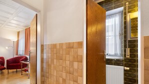 A hotel room with a tiled wall, a radiator, a window with curtains, and a red chair. - Apartment '4' with Wi-Fi (Lindau)