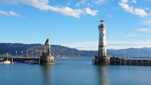 A lighthouse and statue on a pier with calm water and a clear sky. - Apartment '6' with Wi-Fi (Lindau)
