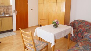 A dining area with a table, chairs, a cabinet, and a sofa.