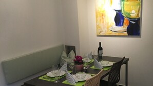 A dining area with a table set for four, a bench, and a painting on the wall. - Apartment 'Unterm Blauregen' with Private Terrace and Wi-Fi (Öhningen)
