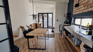 Een moderne keuken met een houten eettafel, zwarte stoelen en een accentmuur van baksteen.
