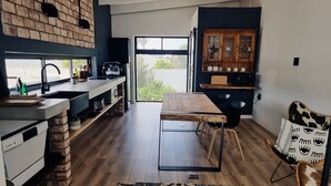 Een moderne keuken met een bakstenen muur, een groot raam en een eethoek met een tafel en stoelen.
