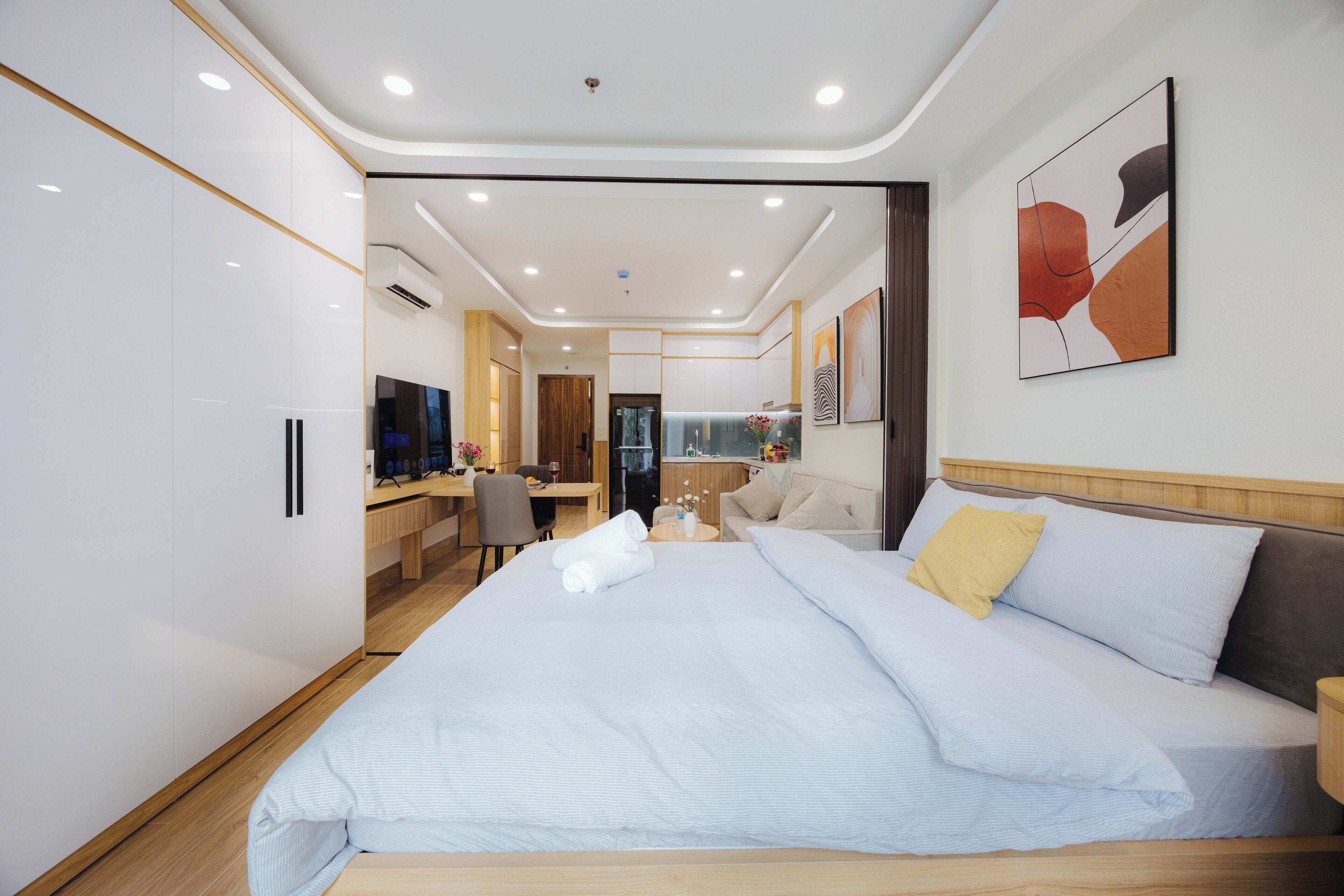 A modern hotel room with a large bed, a desk, and a seating area.