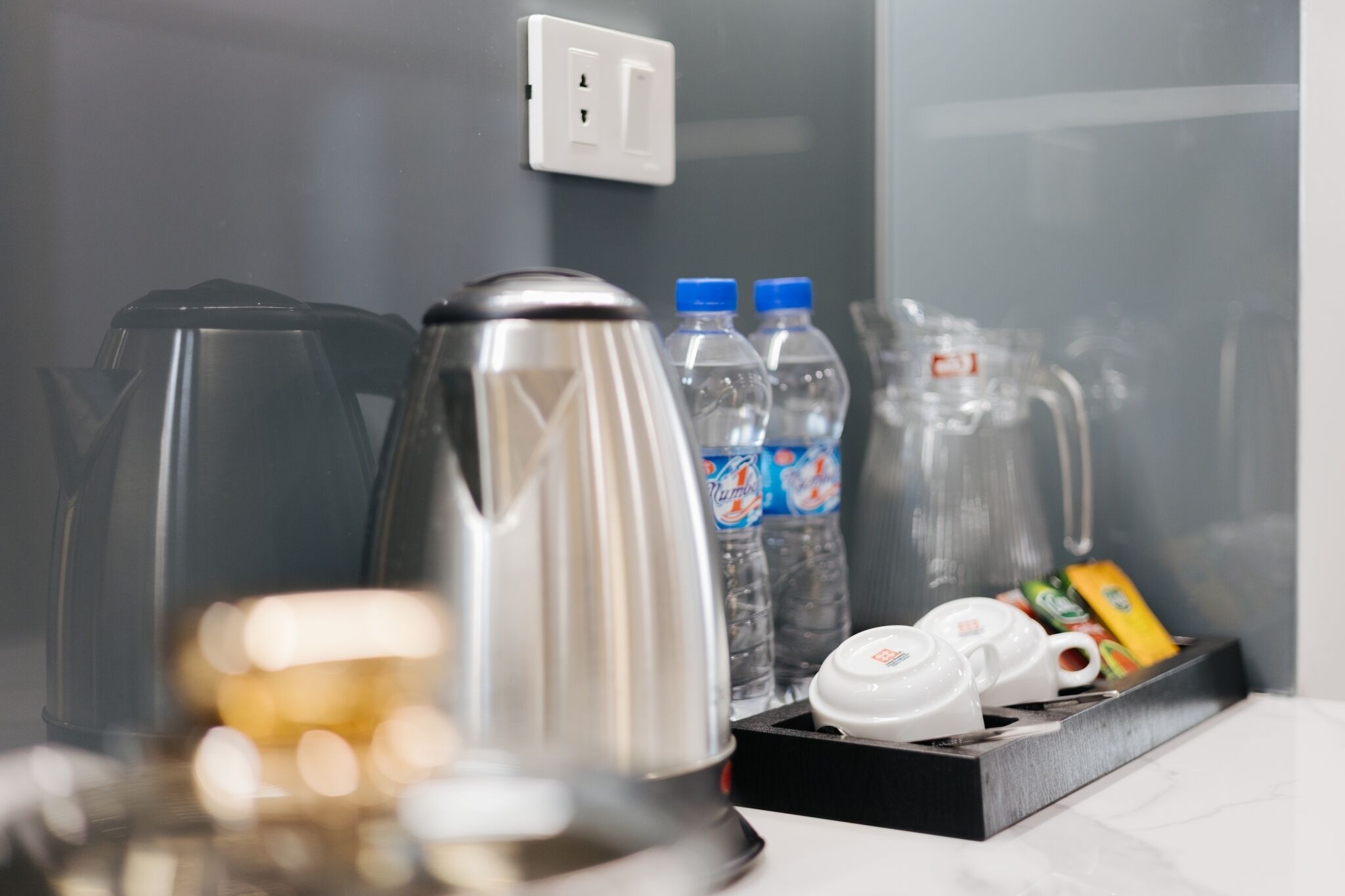Une petite cuisine équipée d’une machine à café, de bouteilles d’eau et d’un service à thé.