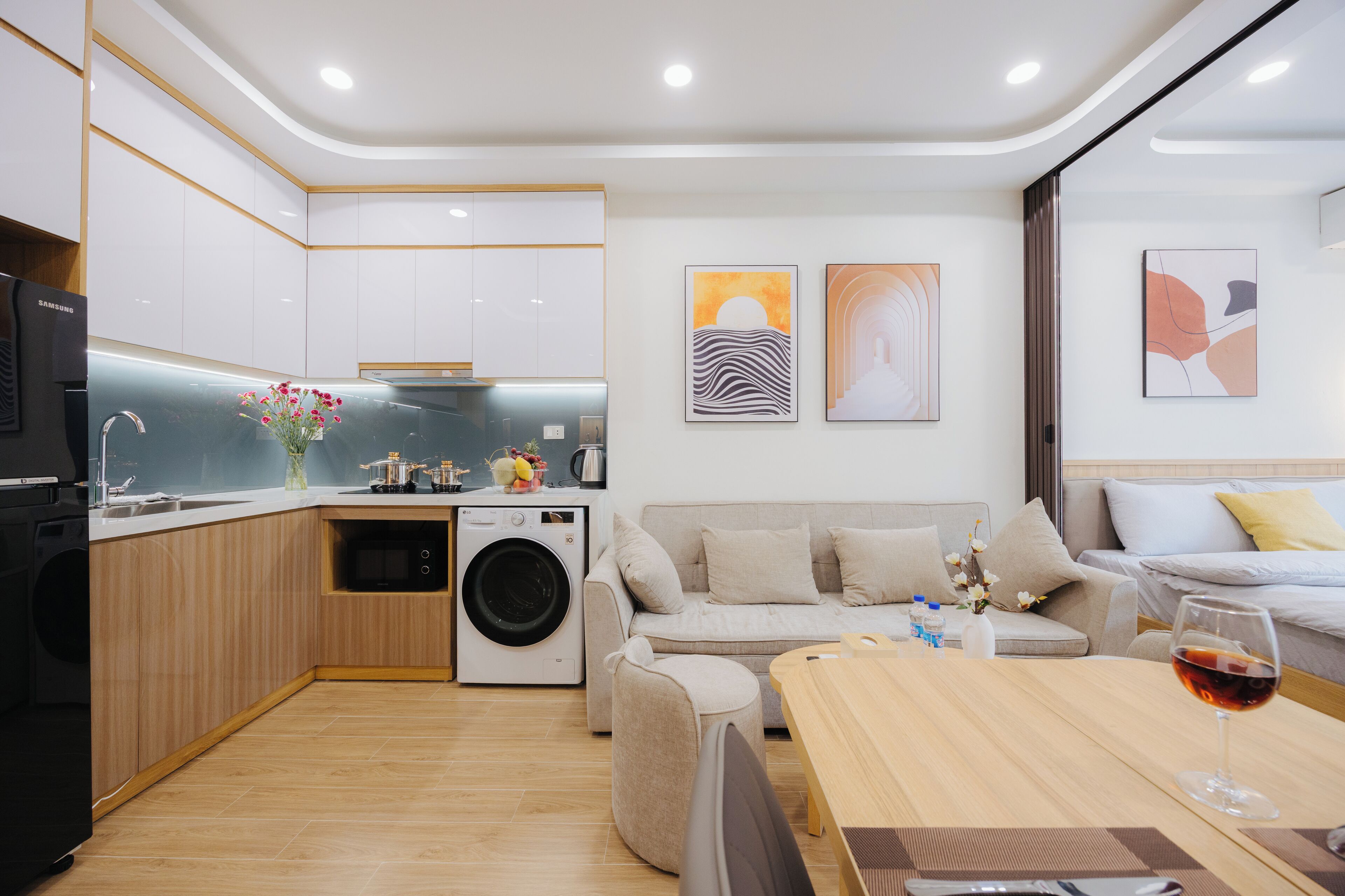 Une cuisine moderne équipée d’un lave-linge, un coin repas avec une table et des chaises, et un espace de vie avec un canapé et un lit.