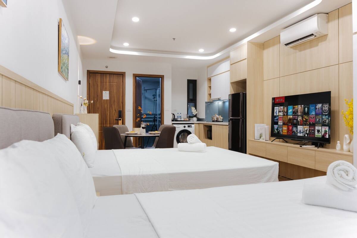 Habitación de hotel con cama, escritorio, lavadora, televisor y aire acondicionado instalado en la pared.