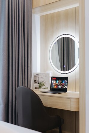 Una habitación moderna con un escritorio, una computadora portátil, un espejo redondo y una revista.