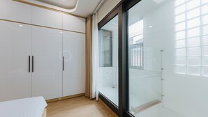 Un dormitorio moderno con un armario espacioso, cabina de ducha de vidrio y vistas al exterior.