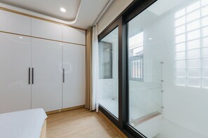 A modern bedroom with a large wardrobe, a glass shower enclosure, and a view of the outside. - Wisteria Luxury Apartment (Hanoi)