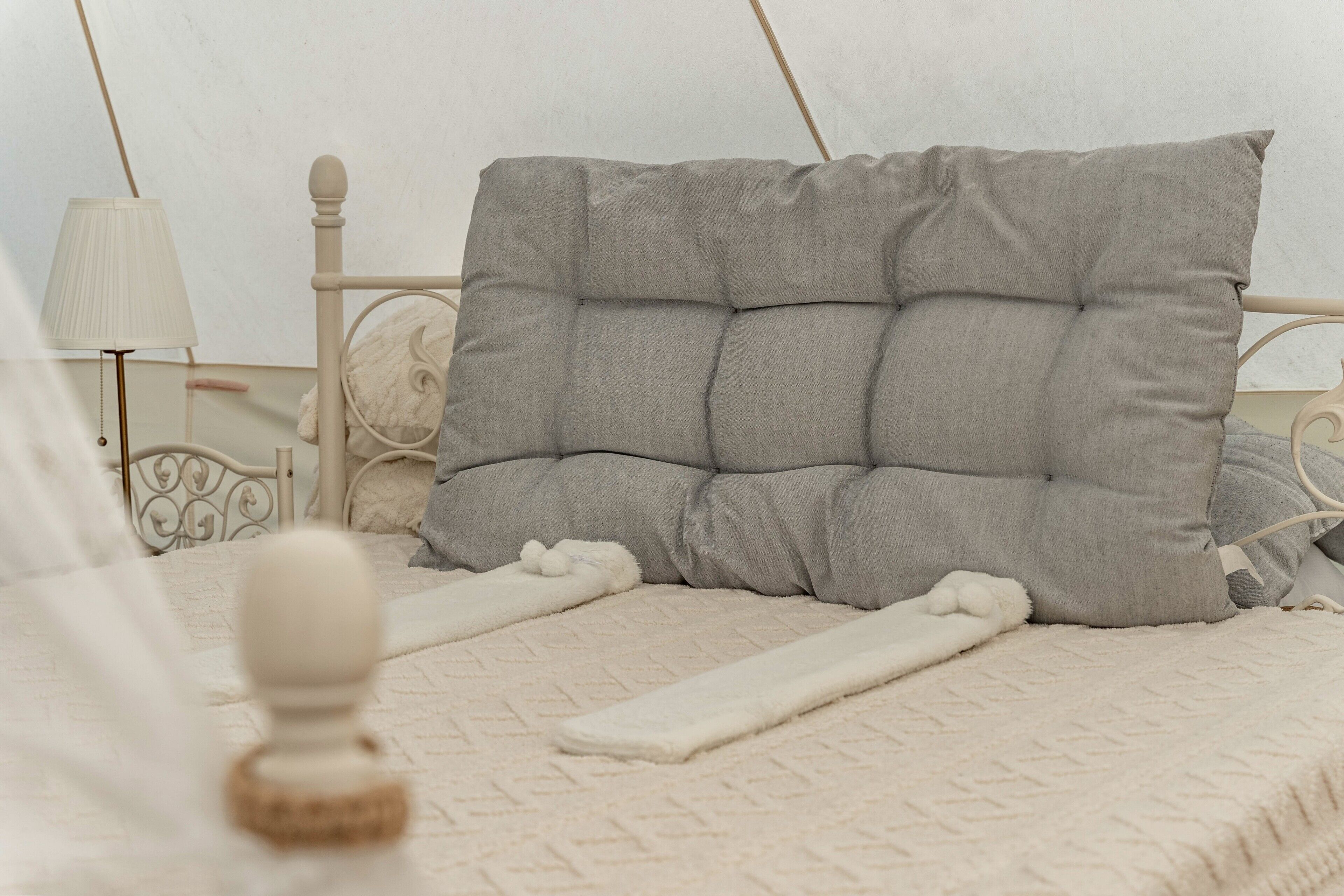 Un lit avec une tête de lit, une lampe de chevet et une couverture blanche.