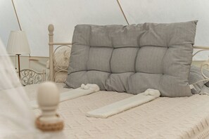 Un lit avec une tête de lit, une lampe de chevet et une couverture blanche.