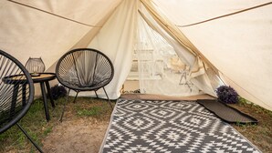 Une tente à l’intérieur de laquelle se trouvent une chaise noire et un tapis à motifs.