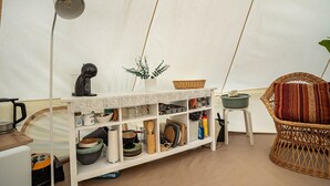 Une pièce avec une étagère blanche, une chaise en osier et une lampe.