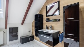 A modern bathroom with a large mirror, black cabinets, a white sink, and a wooden accent wall. - Holiday Apartment 'Waldmann' with Shared Terrace, Garden, and Wi-Fi (Hattorf am Harz)
