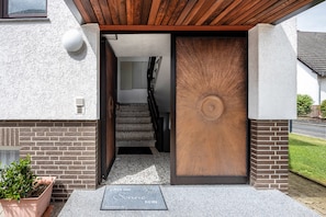 Uma fachada moderna de edifício com porta de madeira, escada e planta em vaso.