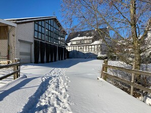 A snow-covered pathway leading to a building with large windows and a brick facade.