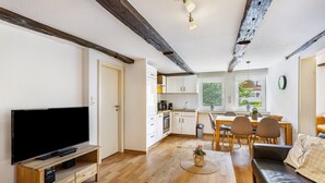 A modern living room with a flat-screen TV, wooden coffee table, and a sofa. - Holiday Apartment '3, 53sqm' with Shared Terrace, Shared Garden and Wi-Fi (Schmallenberg)