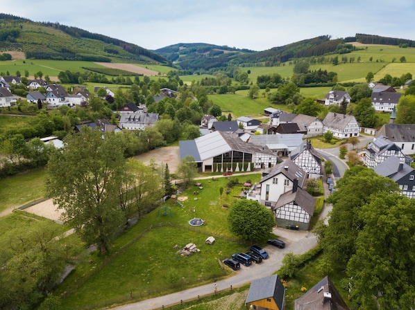 A rural village with traditional half-timbered houses, a central building with a sloped roof, and a playground.