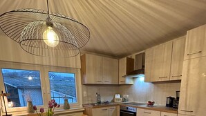A modern kitchen with wooden cabinets, a dining table set with plates and bowls, and a pendant light. - Holiday Apartment '6, 85sqm' with Shared Terrace, Shared Garden and Wi-Fi (Schmallenberg)