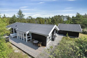 Moderni talo, jossa on terassi, suuret ikkunat ja katettu ulkotila oleskelua varten.