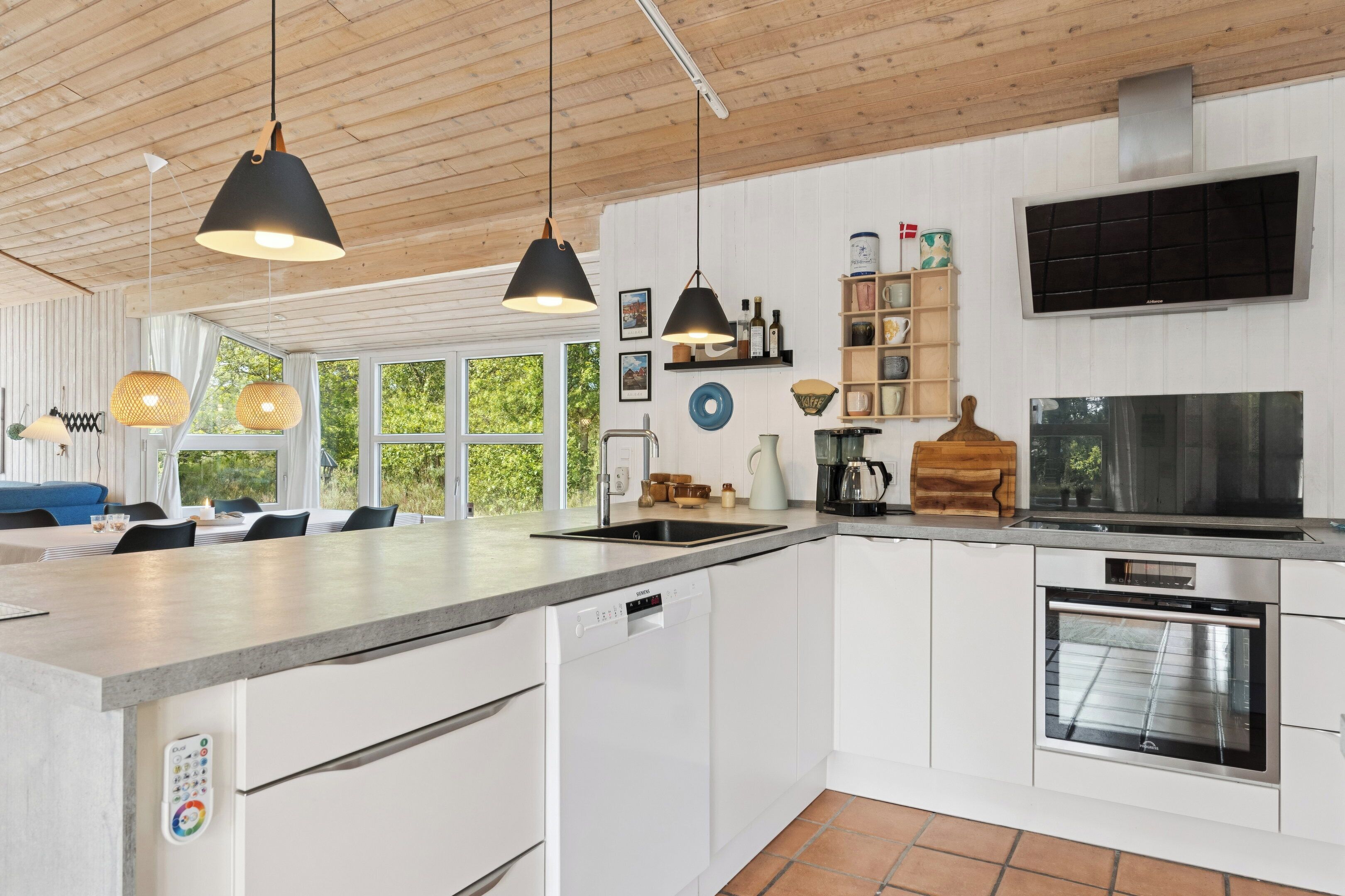 Een moderne keuken met een groot kookeiland, een inbouwoven en hanglampen.