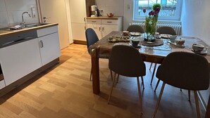 A dining area with a wooden table, chairs, and a hanging light fixture. - Holiday Apartment '1, 70sqm' with Shared Terrace, Shared Garden and Wi-Fi (Schmallenberg)