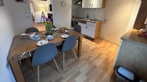 A dining area with a wooden table, chairs, and a vase of flowers. - Holiday Apartment '1, 70sqm' with Shared Terrace, Shared Garden and Wi-Fi (Schmallenberg)