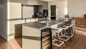 Une cuisine moderne dotée d’un plan de travail en marbre, d’appareils électroménagers en acier inoxydable et d’un réfrigérateur à vin.