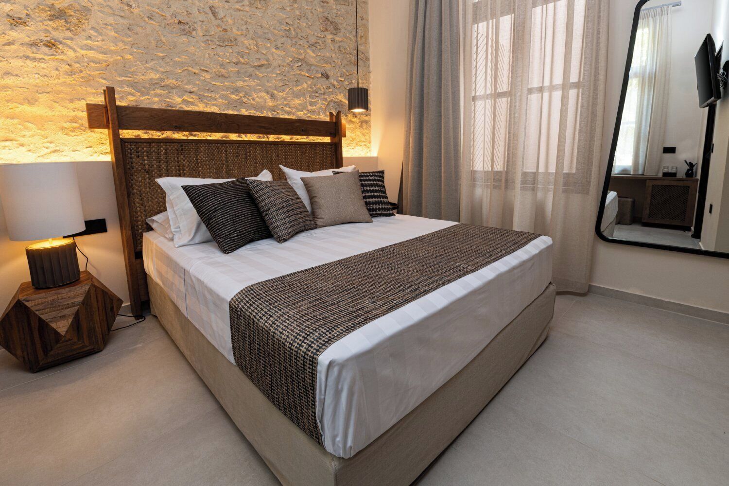 A bed with a wooden headboard, a bedside lamp, and a mirror on the wall.