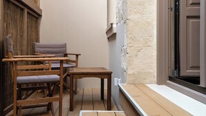 Una terraza de madera con un banco y una mesa, una valla de bambú y una puerta con pared texturizada.